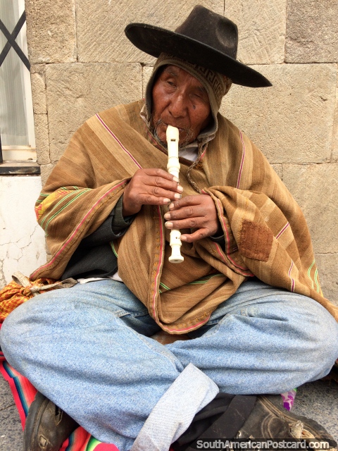 O homem com um chapéu preto joga o registrador, que atua na rua na rua em Puno. (480x640px). Peru, América do Sul.