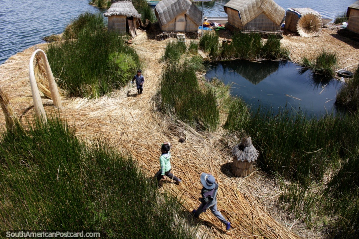 Los nios juegan y corren alrededor de su casa de la isla de caa flotante, Lago Titicaca, Puno. (720x480px). Per, Sudamerica.
