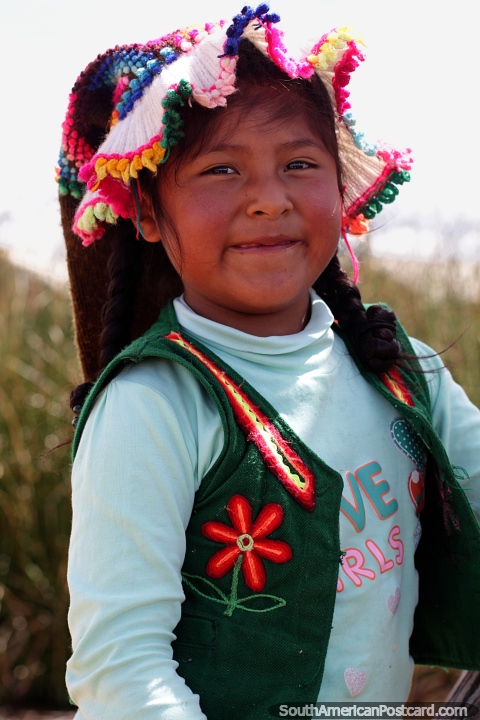 Young Uros girl with traditional head wear and a big smile at Suma Kurmi Island in Puno. (480x720px). Peru, South America.