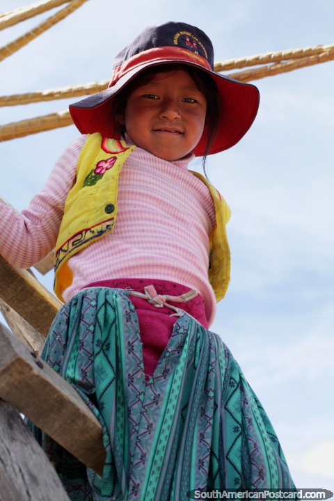 A menina olha abaixo de uma escada de mão, as pessoas de Uros das ilhas flutuam em Puno. (480x720px). Peru, América do Sul.