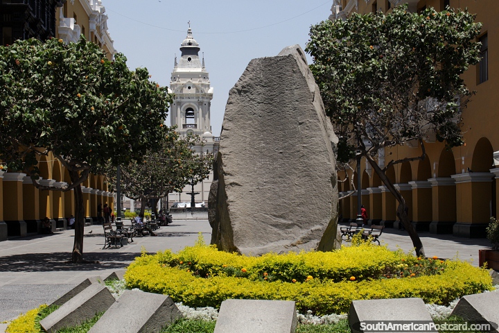 Andean Basal Stone, huge rock on display and the distant cathedral in Lima. (720x480px). Peru, South America.