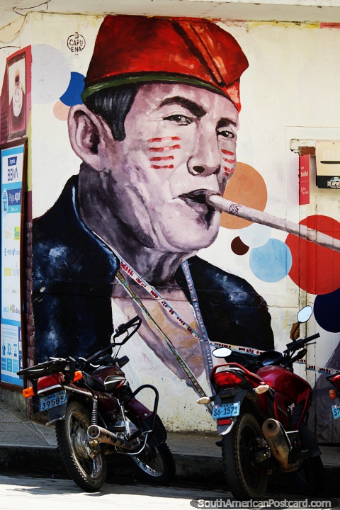 Hombre con pintura facial rayada de rojo y tocado toca una flauta, arte callejero en Lamas. (480x720px). Per, Sudamerica.