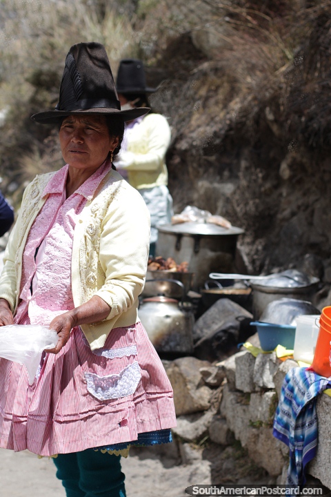 Indigenous woman with a tall hat cooks outside in the mountains in Caraz. (480x720px). Peru, South America.