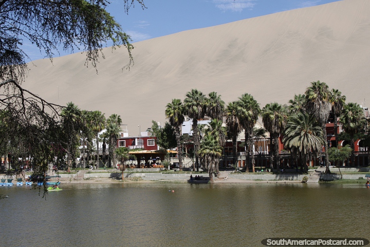 Hotels, restaurants, palm trees and sand around the lagoon at Huacachina. (720x480px). Peru, South America.
