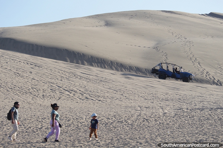 People walk to buggy station to ride around the sand dunes in Huacachina. (720x480px). Peru, South America.