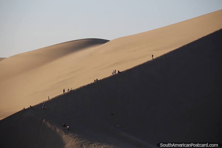 As pessoas sobem aos picos das dunas para o pr do sol em Huacachina. (720x480px). Peru, Amrica do Sul.