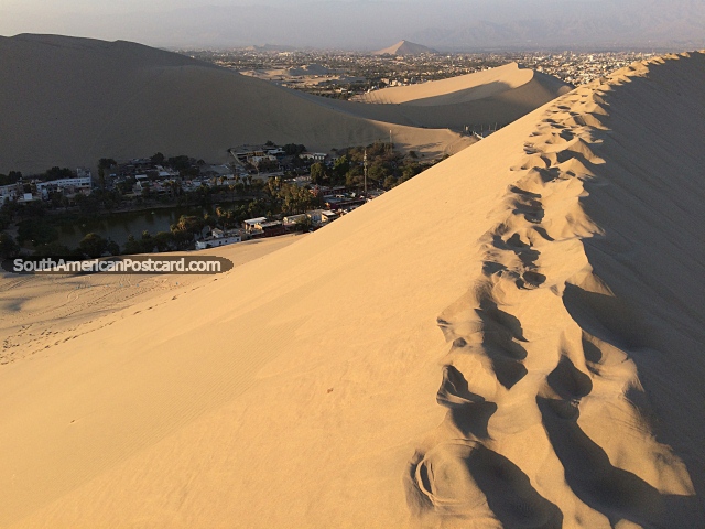 Huacachina / Ica, Peru - Sandboarding The Sand Dunes In An Oasis. People come to Huacachina to stay beside the lagoon surrounded by huge sand dunes. It's peaceful here indeed. At least until you go sand-boarding on those dunes!
