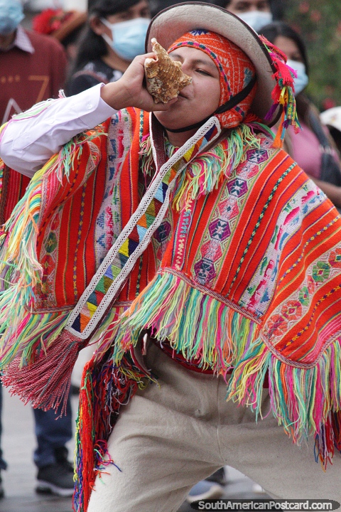 Homem sopra uma concha, vestido com um xale laranja em Cusco. (480x720px). Peru, Amrica do Sul.