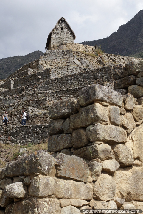 Choza de piedra en la parte superior de la fortaleza de piedra Inca de Machu Picchu. (480x720px). Perú, Sudamerica.