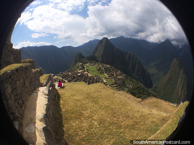 Mulher indígena em rosa senta-se com vista para Machu Picchu. (640x480px). Peru, América do Sul.
