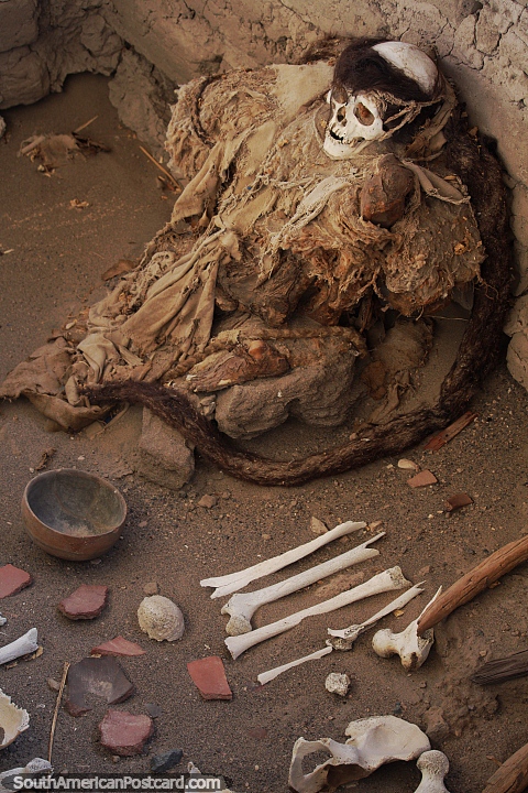 Uma múmia em um poço com ossos e cerâmica quebrada no cemitério de Chauchilla em Nazca. (480x720px). Peru, América do Sul.