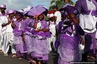Kids dressed in purple and white, some with fans, the Avondvierdaagse parade in Paramaribo, Suriname.