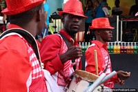 Os janotas com chapéus vermelhos abandonam os polegares na pompa de Avondvierdaagse em Paramaribo, Suriname. As 3 Guianas, América do Sul.