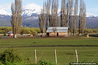 Celeiro em uma fazenda, grupo de cavalos, tanque de água e uma visão bonita do caminho fora de Trevelin a borda. Argentina, América do Sul.