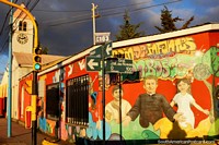Versão maior do Esquina da rua colorida em Ushuaia com arte de rua impressionante e a torre do relógio.