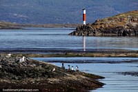 Red and white lighthouse and a beautiful scene in the Ushuaia harbor. Argentina, South America.