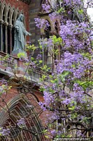 Figure of Jesus above the main door at the Church of the Capuchins in Cordoba, tree with purple flowers. Argentina, South America.