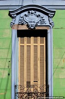 Yellow wooden window shutters surrounded by blue ceramic, a green wooden wall and black iron, house facade in Parana. Argentina, South America.