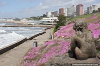 Girl of bronze sits upon a rock and gazes out to sea in Mar del Plata. Argentina, South America.