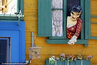 A mulher tende as suas flores de uma janela, uma fachada clássica em La Boca, Buenos Aires. Argentina, América do Sul.
