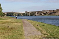 Peaceful walk along the waterfront by the river in Viedma, a distant bridge. Argentina, South America.