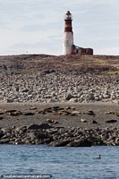 Penguin Island with the lighthouse and seals on the beach, Puerto Deseado. Argentina, South America.
