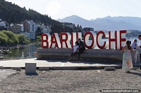 Grandes letras vermelhas soletram Bariloche, um lugar para uma foto à beira do lago. Argentina, América do Sul.
