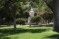 Woman holds a torch, tall white monument in Mayo Park, San Juan, with nice green lawns.