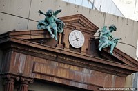 Pair of bronze-green angels on each side of a clock, a monument in Rosario.
