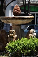 Monkey and pineapple fountain in Cordoba, a bird visits for a drink. Argentina, South America.