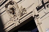 Art-deco building facade with a ceramic head and face above the doorway in Corrientes.