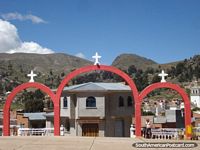 El aspecto de la iglesia en Copacabana a través de las arcos rojas hacia las montañas. Bolivia, Sudamerica.