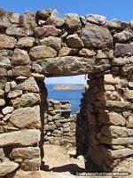 Rock doorway of Inca ruins looks out to small island at Lake Titicaca. Bolivia, South America.