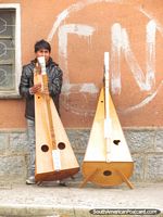 Homem com 2 grandes instrumentos de corda em Potosi. Bolívia, América do Sul.