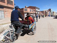 Bicycle-taxi carries a woman along the street in Desaguadero. Bolivia, South America.