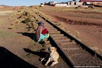 A woman and her dog sit beside train tracks between Tiwanaku and La Paz.