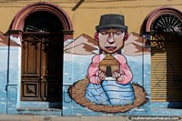 La mujer sostiene una pajarera, un gran mural de entre 2 puertas antiguas en Cochabamba. Bolivia, Sudamerica.