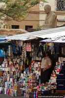 Man sells products on the street below a bust in Tarija.