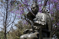 Un hombre que lee un libro, monumento en Tarija, por debajo de los árboles de color púrpura. Bolivia, Sudamerica.