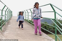 2 girls run over the bridge at the Bermejo botanical gardens.