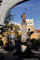 Estatua de oro, fuente negra, arco gris y edificio gubernamental amarillo en Potosí, plaza principal. Bolivia, Sudamerica.