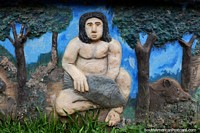 Versão maior do Homem indïgena com um peixe e porco, escultura concreta na praça pública em Riberalta.
