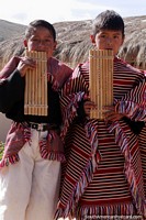 2 niños en ropa tradicional soplan tubos de viento de madera en Puka-Puka. Bolivia, Sudamerica.