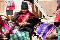 Mujer en ropa tradicional negra y roja tejiendo en el pueblo de Puka-Puka, cerca de Sucre. Bolivia, Sudamerica.