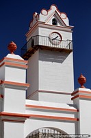 White church beside the plaza in Tarabuco, with clock and bell tower.