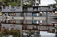 Reflexiones simétricas de un gran bote gris sobre las aguas suaves y sedosas del río Mamore, Trinidad. Bolivia, Sudamerica.