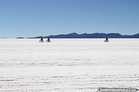 People riding bicycles across the crusty Uyuni salt flats, a hard task. Bolivia, South America.