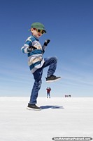 Divirta-se jogando com a perspectiva nos apartamentos de sal de Uyuni, rapaz sobre esmagar uma mulher com o seu pé. Bolívia, América do Sul.