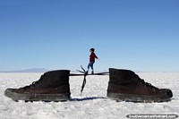 Verso maior do A mulher anda atravs dos cadaros atados de um par de sapatos, uma grande foto mostrando truques perspectivos na fotografia nos apartamentos de sal de Uyuni.