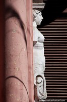 Versão maior do A estátua branca nua incorpora-se na fachada de uma entrada de loja no centro de Oruro.